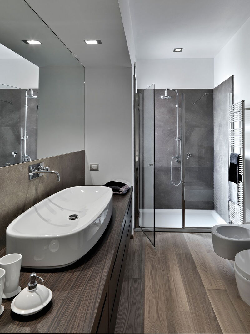 Helles Badezimmer mit Dusche, Waschbecken und sichtbar integrierter Haustechnik